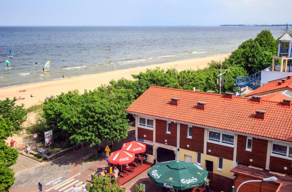 a view of a beach and a building with an umbrella at Yacht Club Residence Sopot in Sopot