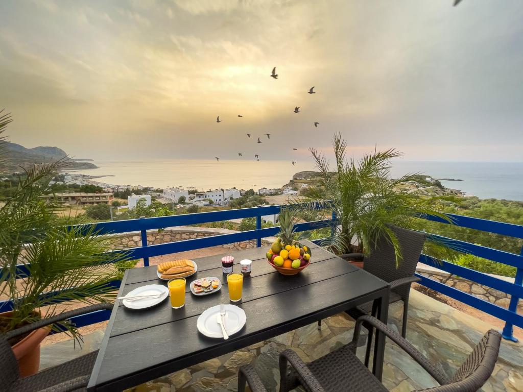 una mesa con comida y bebida en un balcón con vistas al océano en Villa Leonardo en Archangelos