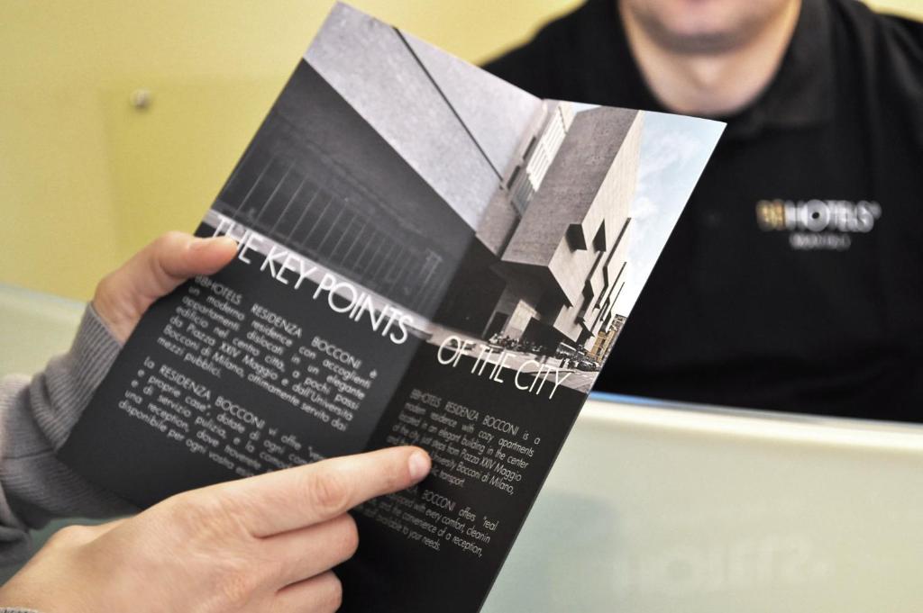 a person holding a book in their hand at BB Hotels Aparthotel Bocconi in Milan