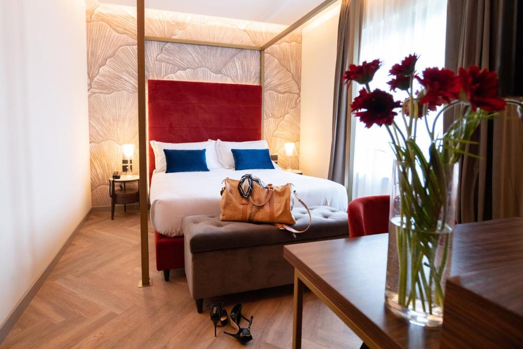 a hotel room with a bed and a vase of flowers at 3T Boutique Hotel in Ivrea