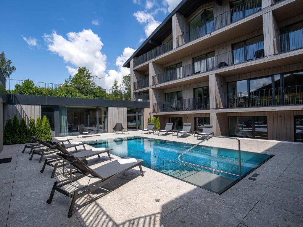 a swimming pool with lounge chairs and a building at Apartment Emma Deluxe Aparthotel-7 by Interhome in Fürth