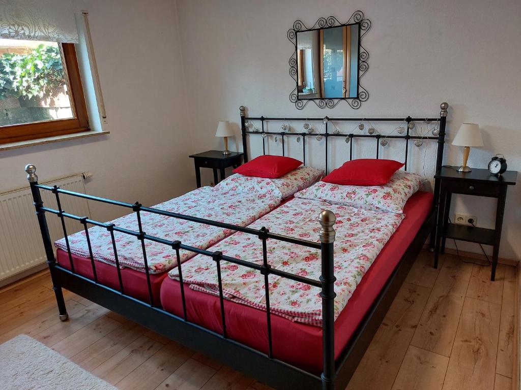 1 dormitorio con cama con almohadas rojas y espejo en Schillerstüble, en Bodelshausen