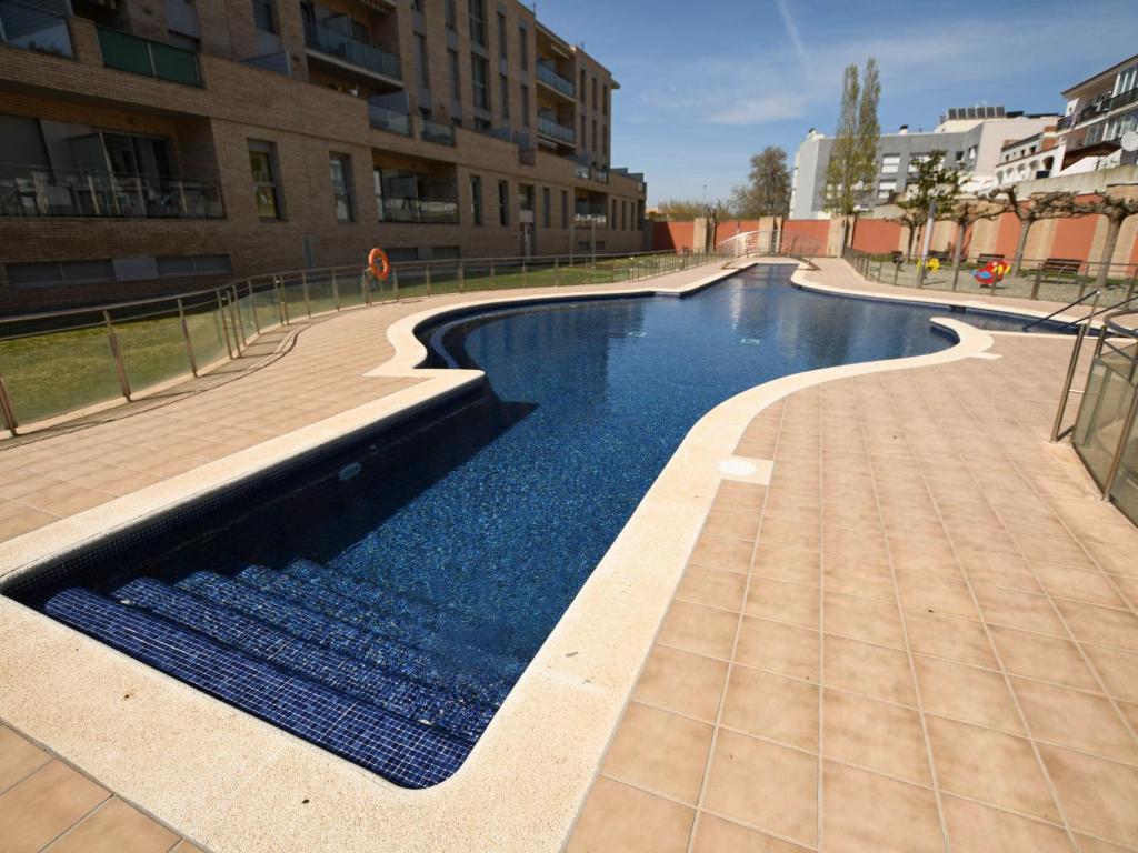 einem Pool mit blauem Wasser vor einem Gebäude in der Unterkunft Apartment PUIG ROM by Interhome in Empuriabrava