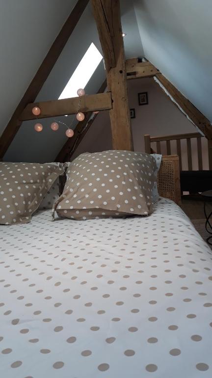 Saint-Pierre-des-ifs的住宿－Gite A la petite Bretonnière，阁楼内的一张带波卡圆点床单和枕头的床