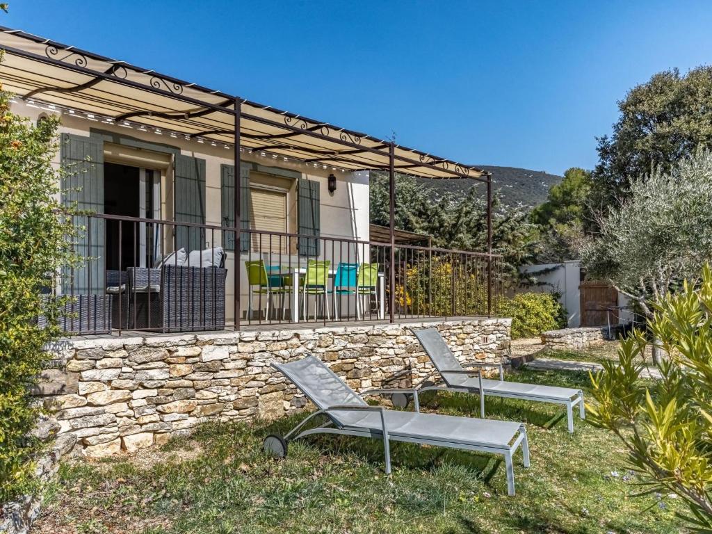 a house with two chairs and a stone wall at Holiday Home La campagne du Colorado by Interhome in Rustrel