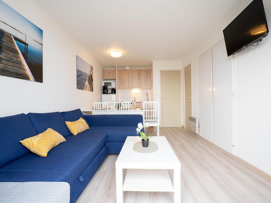 een woonkamer met een blauwe bank en een witte tafel bij Apartment Village Cap Estérel - Le Village-64 by Interhome in Agay - Saint Raphael
