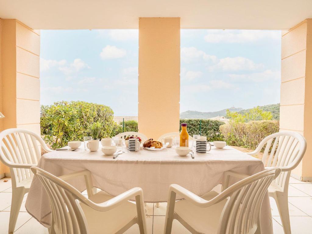 - une table blanche avec des chaises blanches et une table avec de la nourriture dans l'établissement Apartment Les Bastides - I2 047 by Interhome, à Agay
