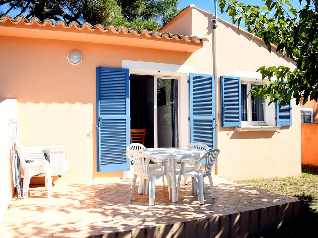 a table and chairs in front of a house with blue shutters at Holiday Home T3 Cabine by Interhome in Borgo