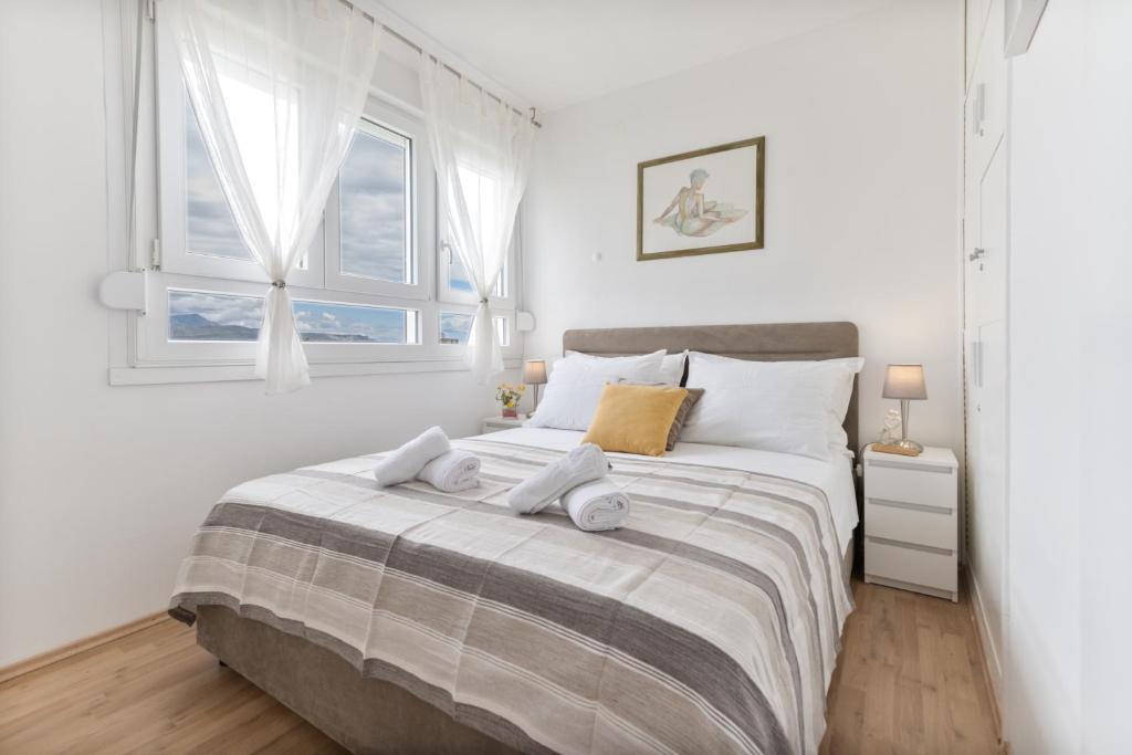 ein weißes Schlafzimmer mit einem großen Bett und zwei Fenstern in der Unterkunft Apartments Plokite in Split