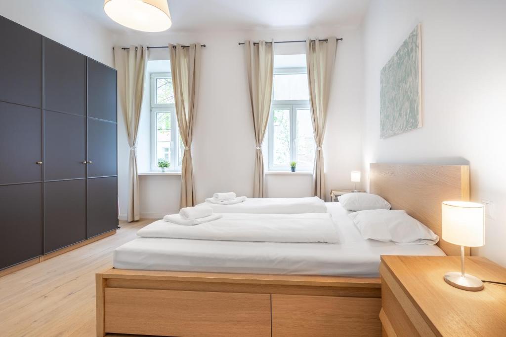 een slaapkamer met een groot bed met witte lakens bij Cottageviertel - Stilvolles Apartment in Parknähe in Wenen