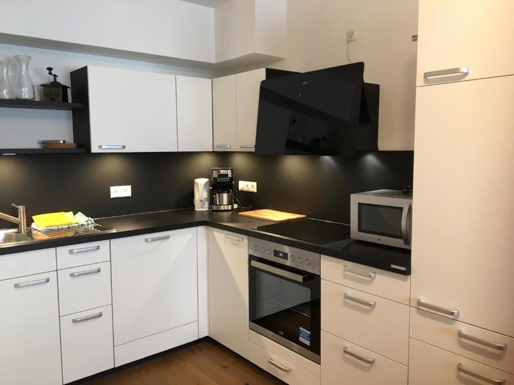 cocina con armarios blancos y microondas en Haus Greet, en Muhr