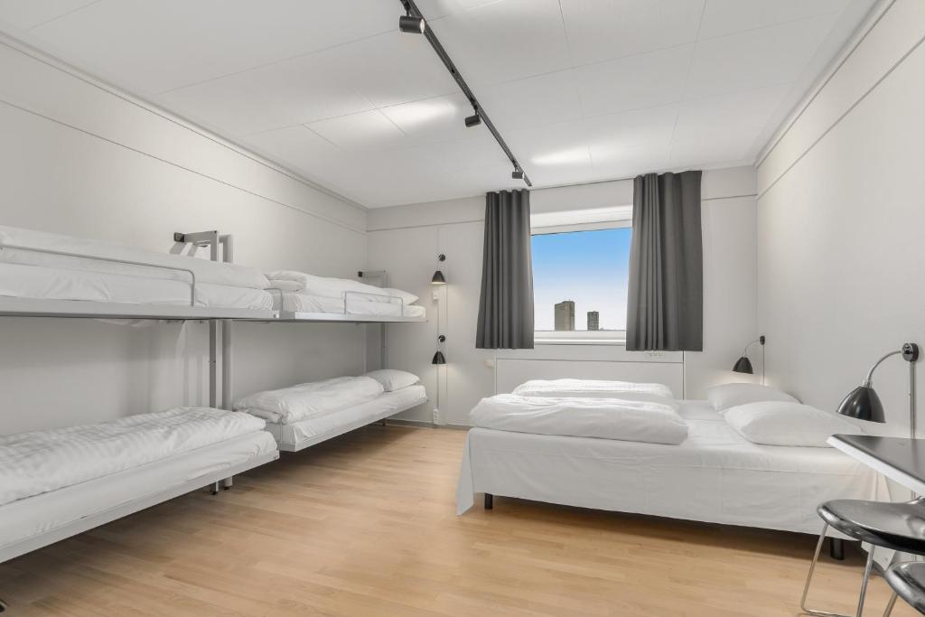 a white bedroom with two bunk beds and a window at Danhostel Copenhagen City & Apartments in Copenhagen