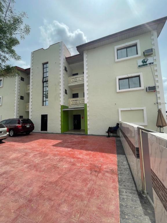a large white building with a red driveway at Alluring View Hotel - Allen Avenue in Lagos