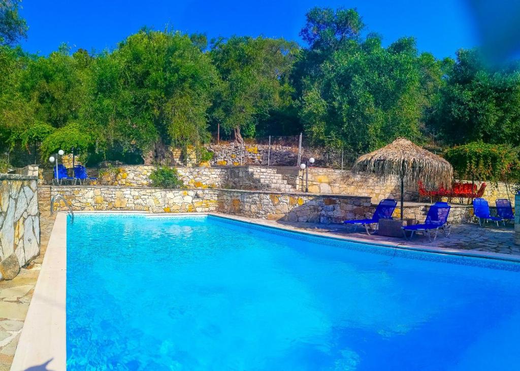 een groot blauw zwembad met stoelen en een parasol bij Villa Alkinoos in Gaios