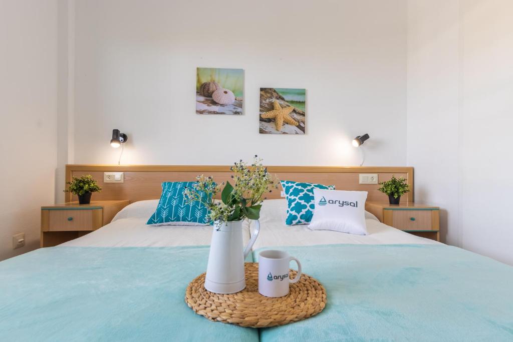 Una cama con dos tazas y una bandeja con flores. en Apartamentos Riviera Arysal, en Salou