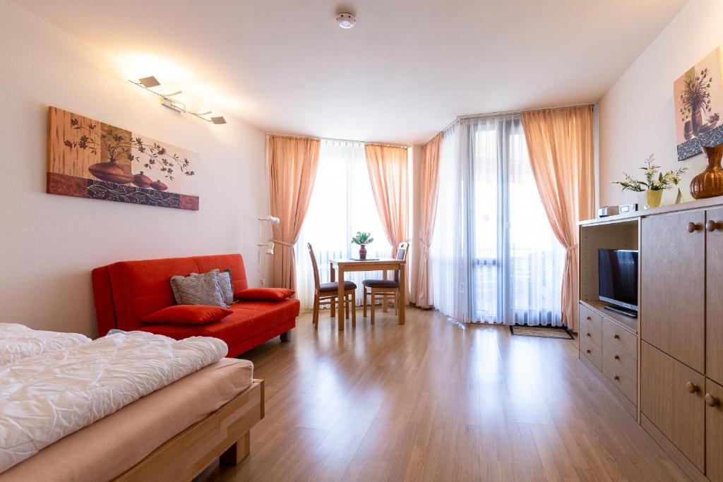 un salon avec un canapé rouge et une télévision dans l'établissement Ferienwohnpark Immenstaad am Bodensee Ein-Zimmer-Apartment 49 41, à Immenstaad am Bodensee