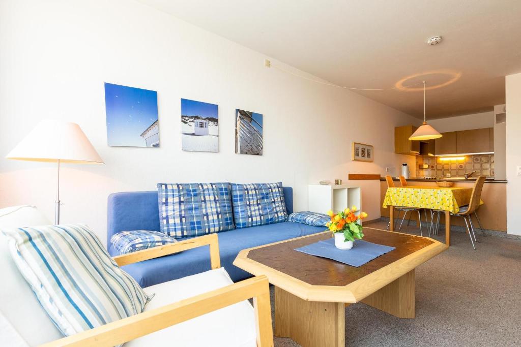 ein Wohnzimmer mit einem blauen Sofa und einem Tisch in der Unterkunft Ferienwohnpark Immenstaad am Bodensee Zwei-Zimmer-Apartment 49 45 in Immenstaad am Bodensee