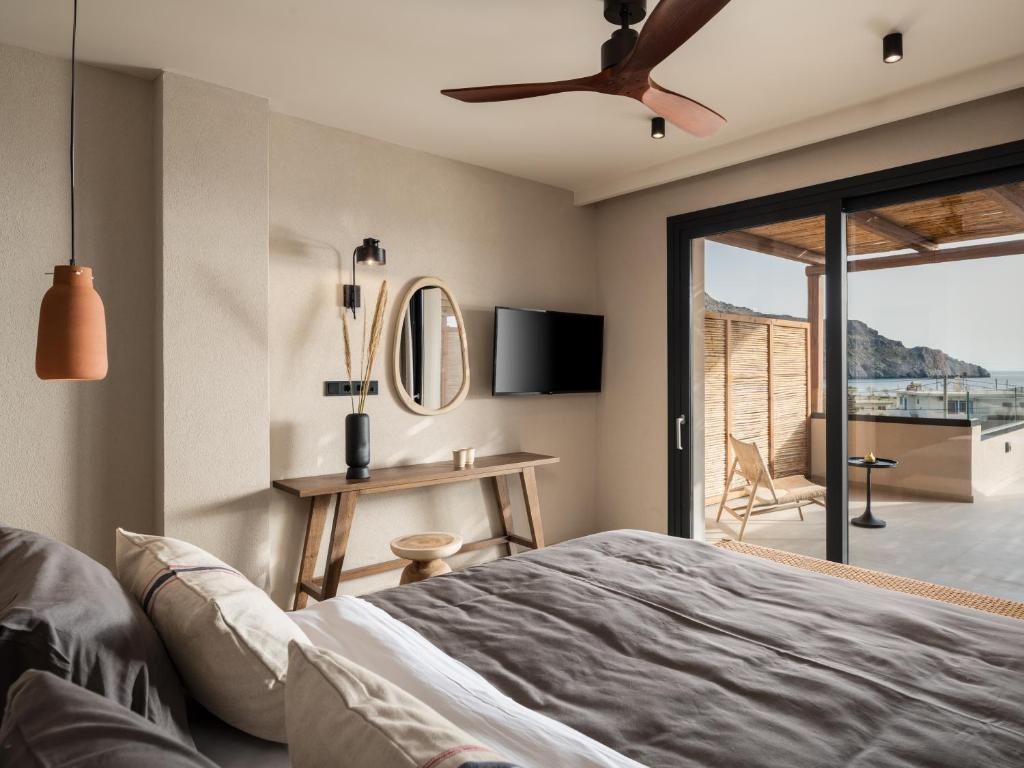 Schlafzimmer mit einem Bett und einem Deckenventilator in der Unterkunft KYMANI Boutique Hotel & Suites in Plakias