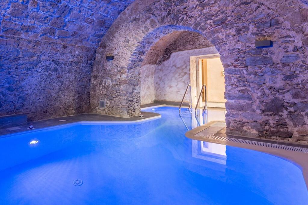 una grande piscina in un edificio con un muro di pietra di Palazzo Cestari Hotel a Montesano sulla Marcellana