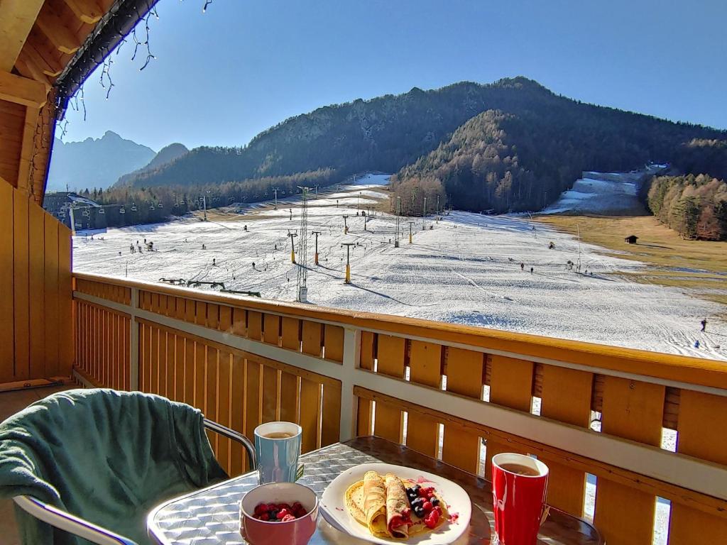 een tafel met een bord eten op een balkon met een skipiste bij Apartma Sonček, on the ski slopes, balcony, private parking in Kranjska Gora