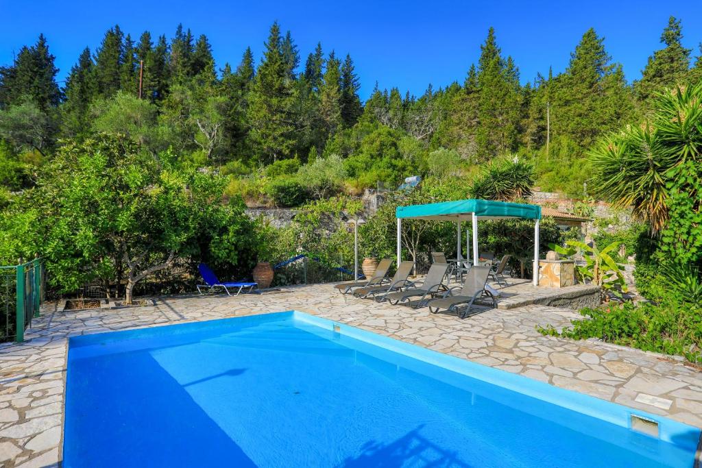 a blue swimming pool with chairs and a umbrella at Villa Sevi in Gaios