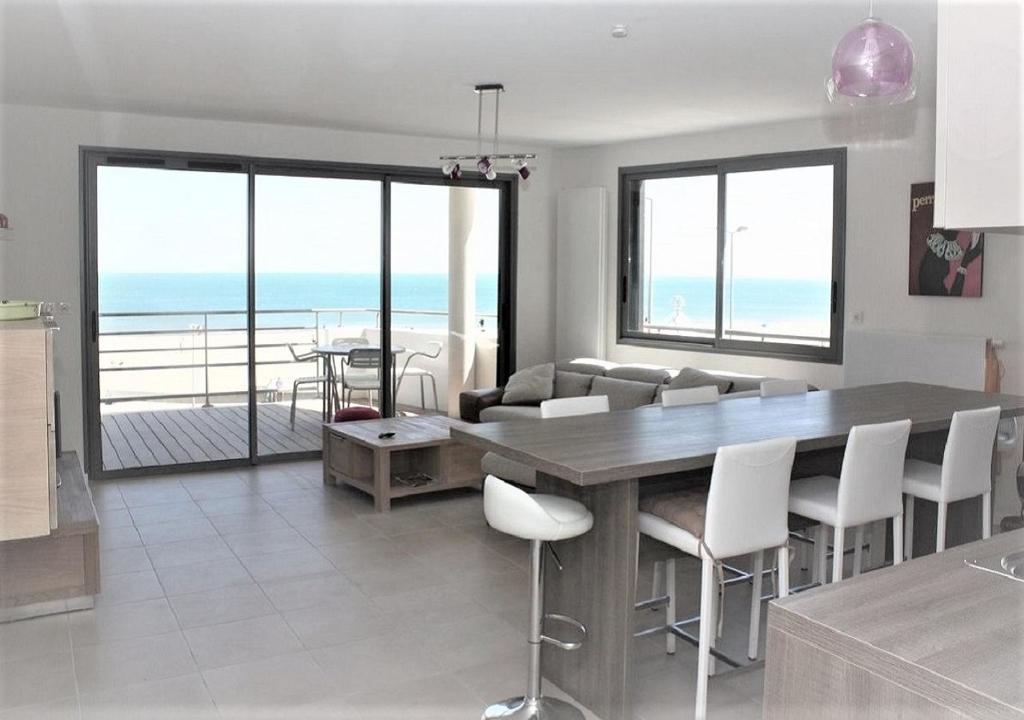 een keuken en een woonkamer met een tafel en stoelen bij La Perle Marine, Luxe et Raffinement, appartement T4 vue mer in Narbonne