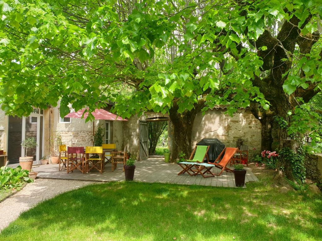 un patio con sillas y mesas bajo un árbol en VILLA VILLOU, en Romanèche-Thorins