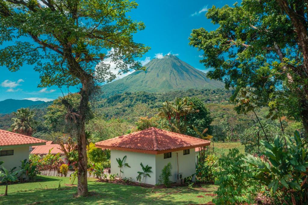 a mountain in the distance with two houses and trees at Miradas Arenal Hotel & Hotsprings in Fortuna