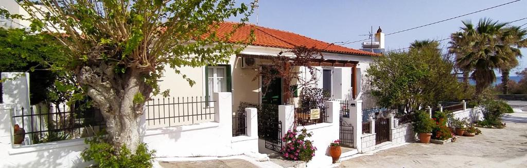 Una casa blanca con un árbol delante. en Kontos-Traditional house in Andros beach, en Ándros