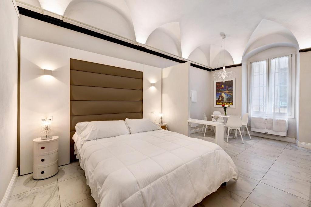ein Schlafzimmer mit einem großen weißen Bett und einem Tisch in der Unterkunft Suite Maribru in Alassio