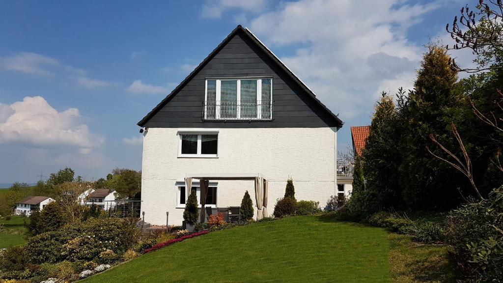 a white house with a black roof on a hill at Ferienwohnung Spier in Ottenstein