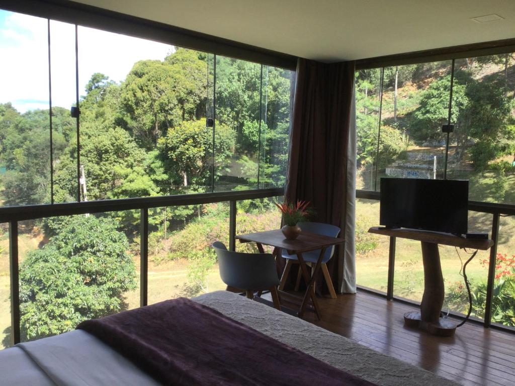 a bedroom with a bed and a large window at Pousada Restaurante Portal do Ceu in Domingos Martins