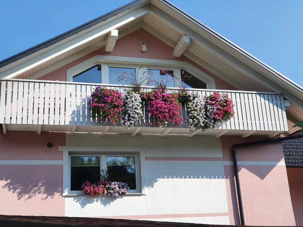 a pink house with flowers on a balcony at Apartma DAVID in Zgornje Gorje