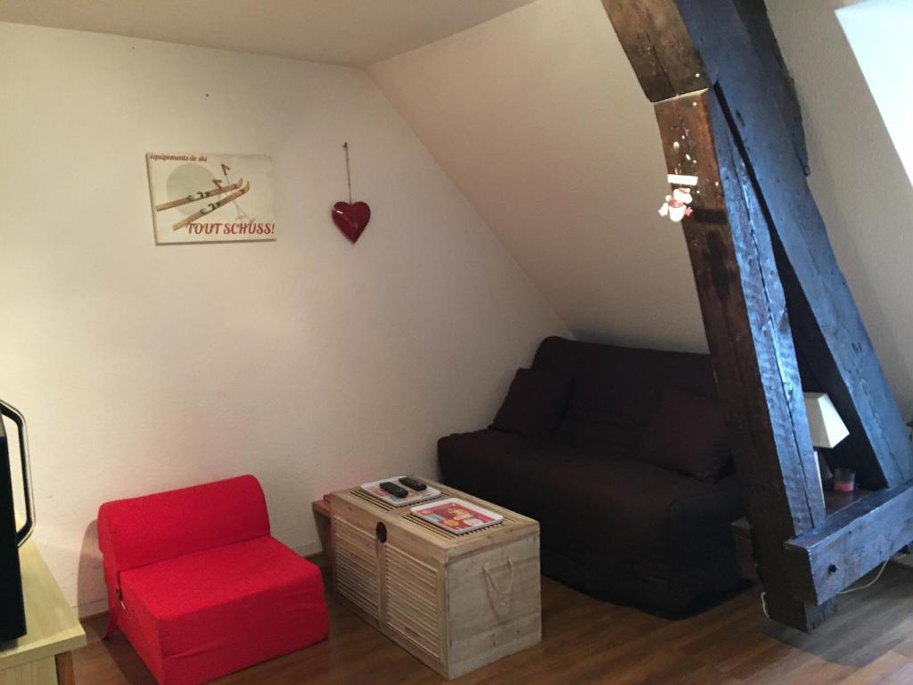a living room with a couch and a red stool at Studio face au Thermes in Le Mont-Dore