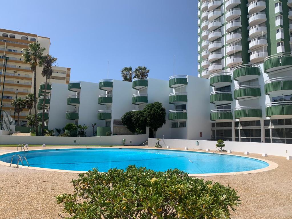 een zwembad voor een hoog gebouw bij Golden Coast Residence in Portimão