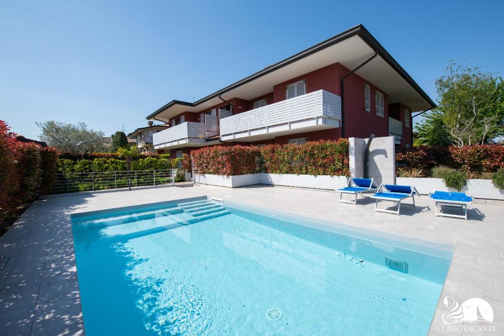 una piscina con 2 sillas azules y una casa en Villa Liliana - App. 06, en Sirmione
