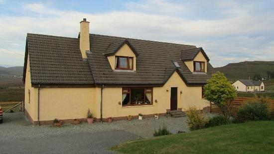 uma casa amarela com um telhado preto em The Thistle Guesthouse em Portree