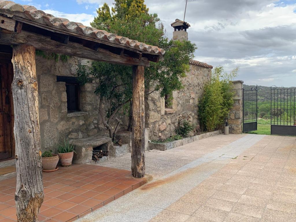 an entrance to a stone building with a wooden pergola at La casita del hortelano in Robledo de Chavela