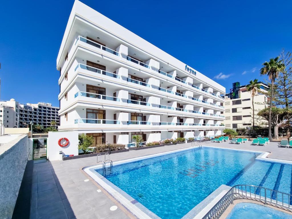 um hotel com piscina em frente a um edifício em Apartamentos Fayna em Playa del Inglés