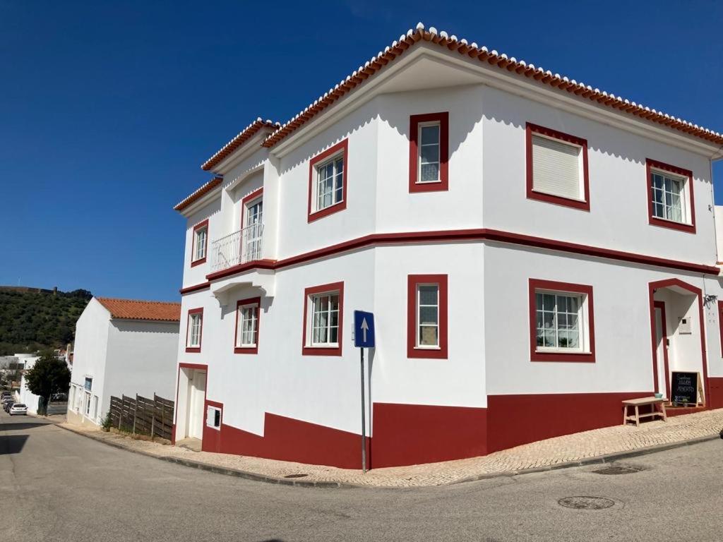 un grand bâtiment blanc et rouge sur le côté d'une rue dans l'établissement Guesthouse Releash Aljezur, à Aljezur
