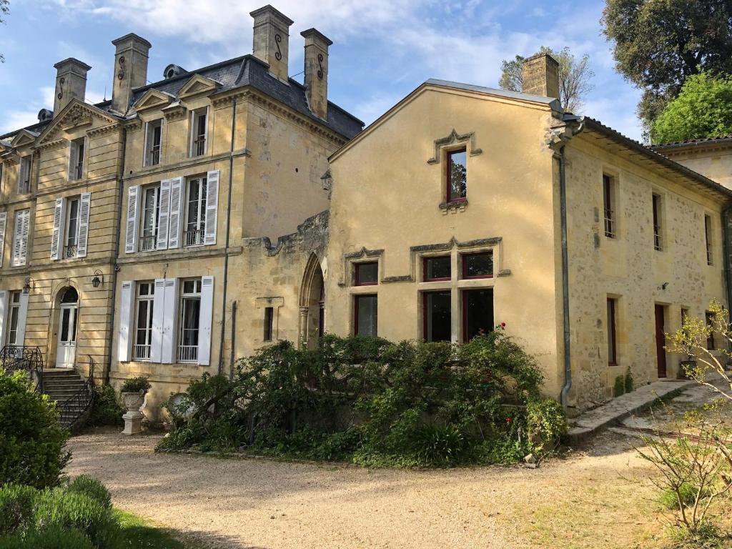 Uma casa velha com um monte de ervas daninhas à frente. em L'abbaye du château du Vallier em Langoiran