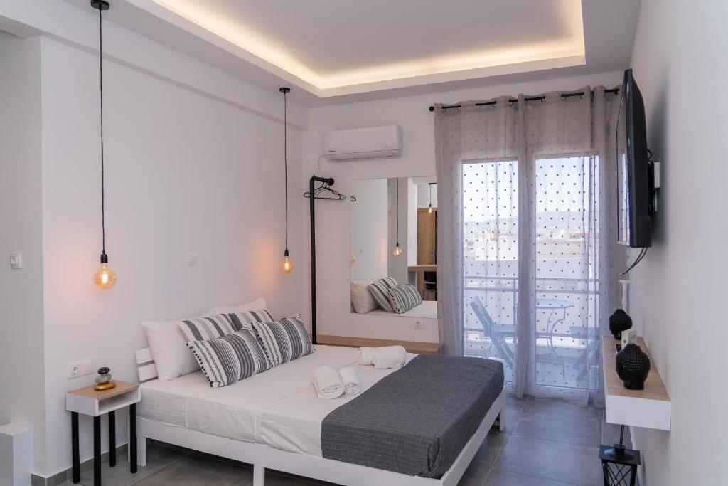 ein weißes Schlafzimmer mit einem Bett und einem großen Fenster in der Unterkunft Cozy Modern Studiο _ Near the Center of Athens in Athen