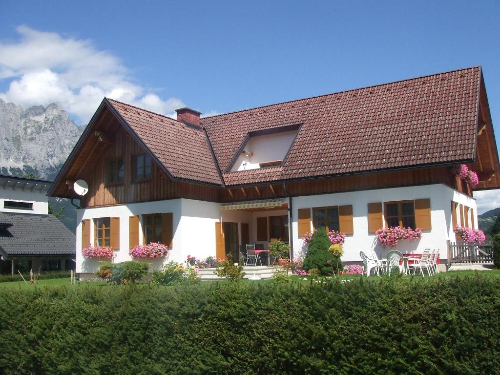 a house with a brown roof and chairs in the yard at Appartement Pölzl Öblarn Region Schladming Dachstein in Öblarn