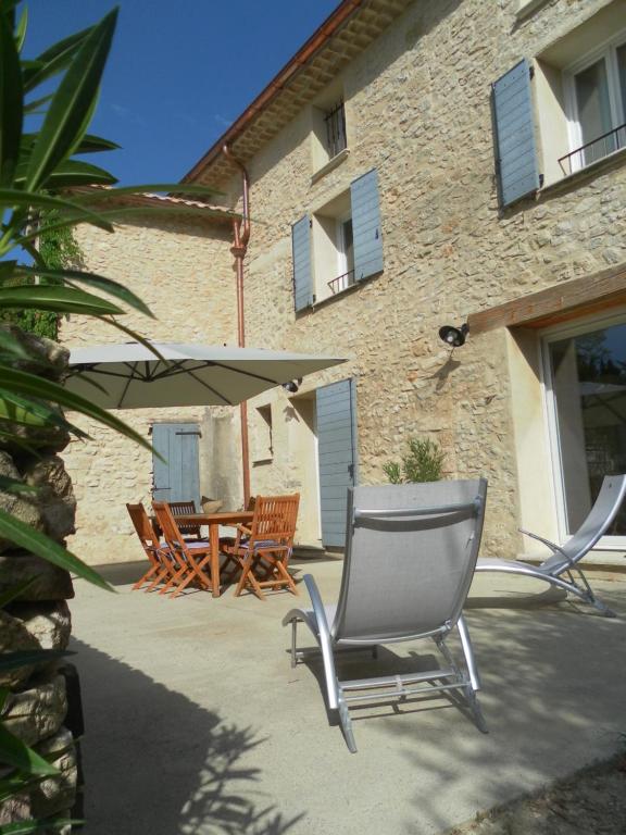 une terrasse avec une table, des chaises et un parasol dans l'établissement Le Mas des Meras - Gite Côté mas, à Lurs