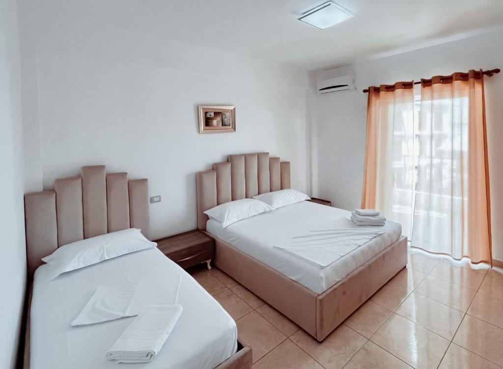 1 dormitorio con 2 camas y ventana en Hotel Nino, en Dhërmi