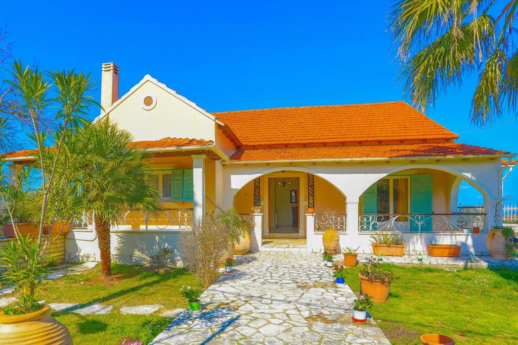 a house with an orange roof and palm trees at Villa Eftihia in Nýmfai