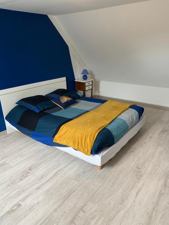 uma cama grande num quarto com uma parede azul em Le Mesnil Normand em Fort-Moville