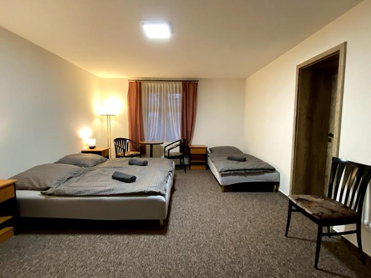 a hotel room with two beds and a table and chairs at Pension Stará hospoda in Dobřív