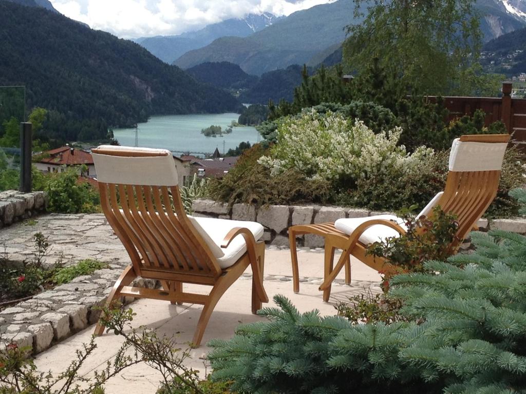 two chairs sitting on a patio with a view of a lake at Fra Rose e Mughi in Domegge di Cadore