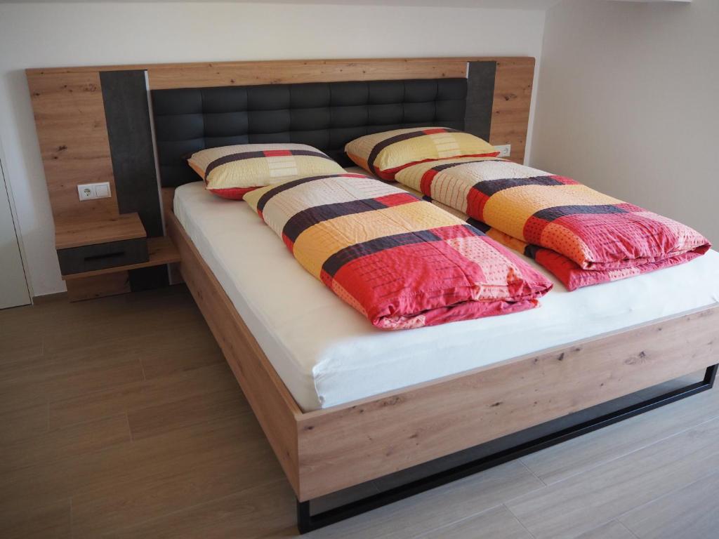 łóżko z drewnianą ramą i 2 poduszkami w obiekcie Ebner Appartements w mieście Aldino